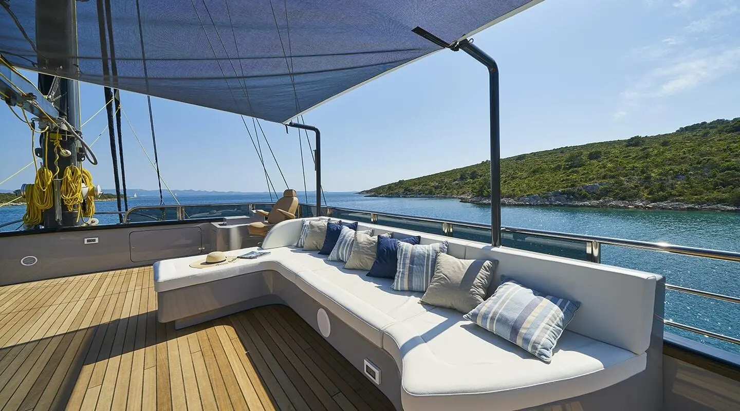 Rara Avis yacht charters aft deck with cushioned seating and blue canopy at sunset