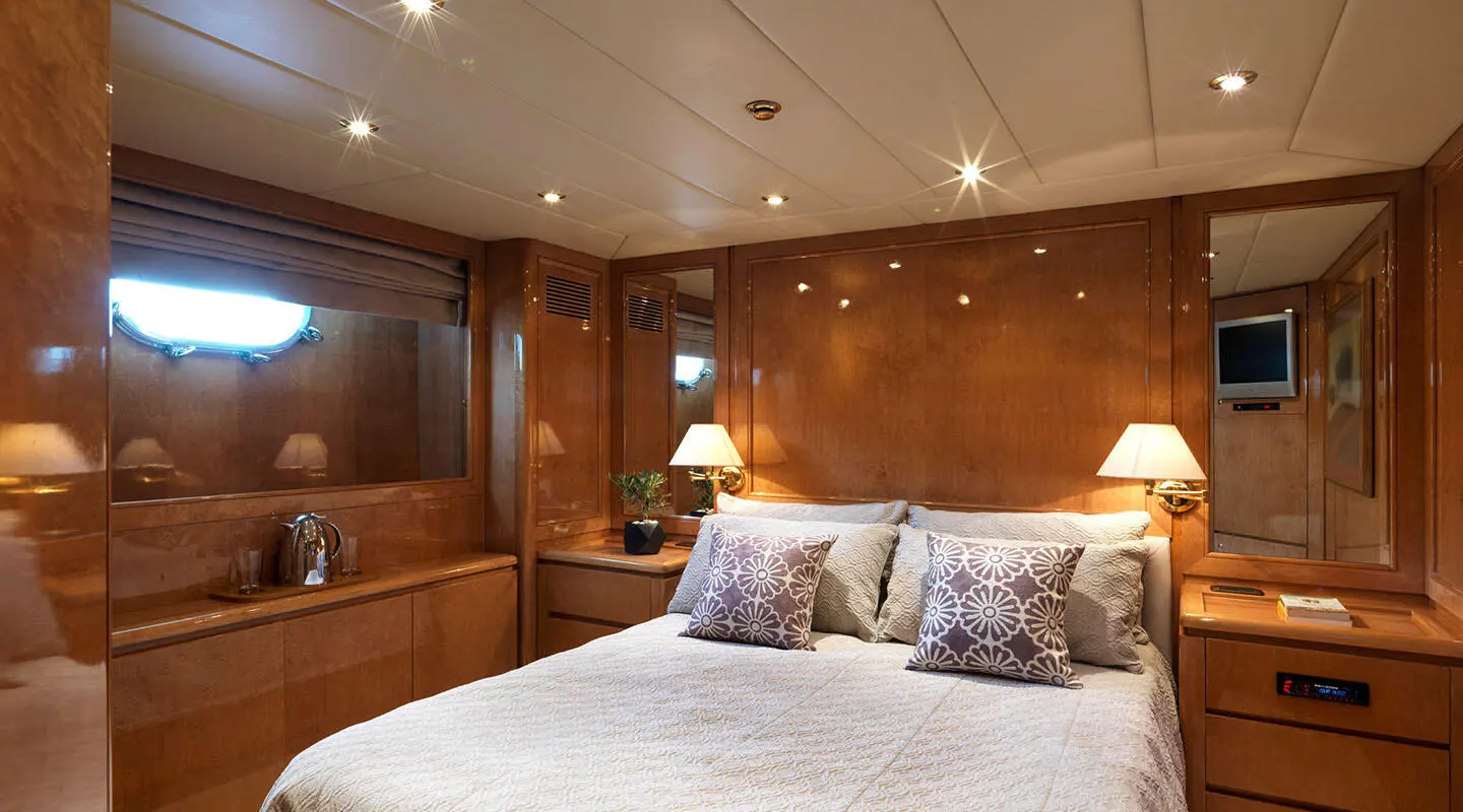 View of a luxurious cabin aboard Idylle yacht with wooden paneling and bed