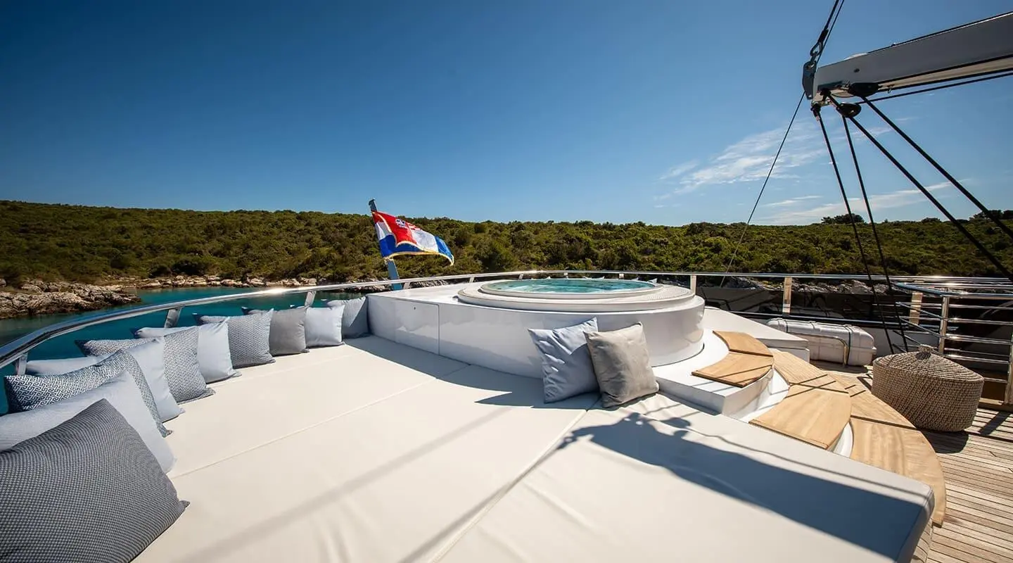 Anima Maris deck at sunrise with white seating and a distant coastline