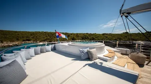 Anima Maris deck at sunrise with white seating and a distant coastline