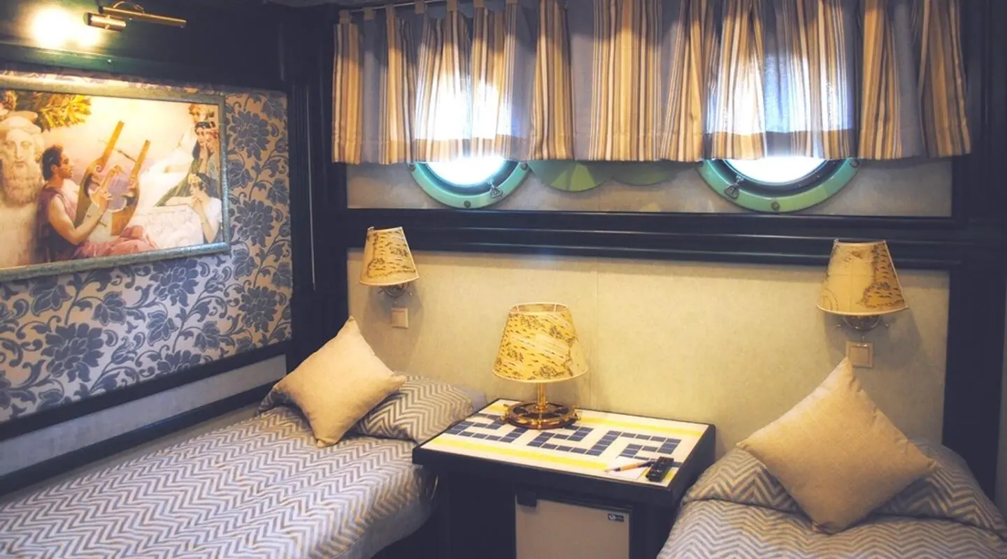 Interior of a gulet cabin with bed, small table, and window view toward deck