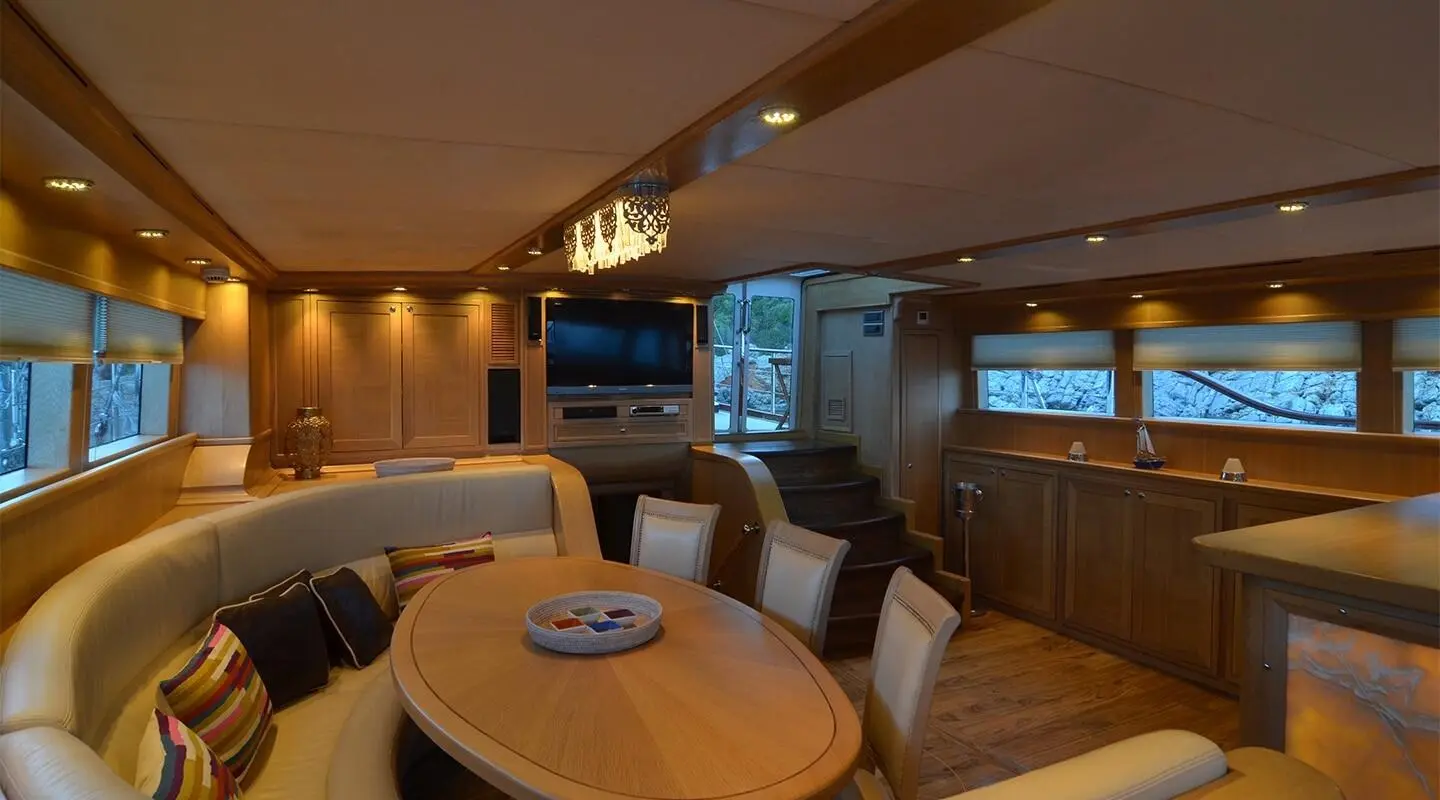 Cozy yacht interior with wooden table, seating, and warm lighting aboard Blue Heaven