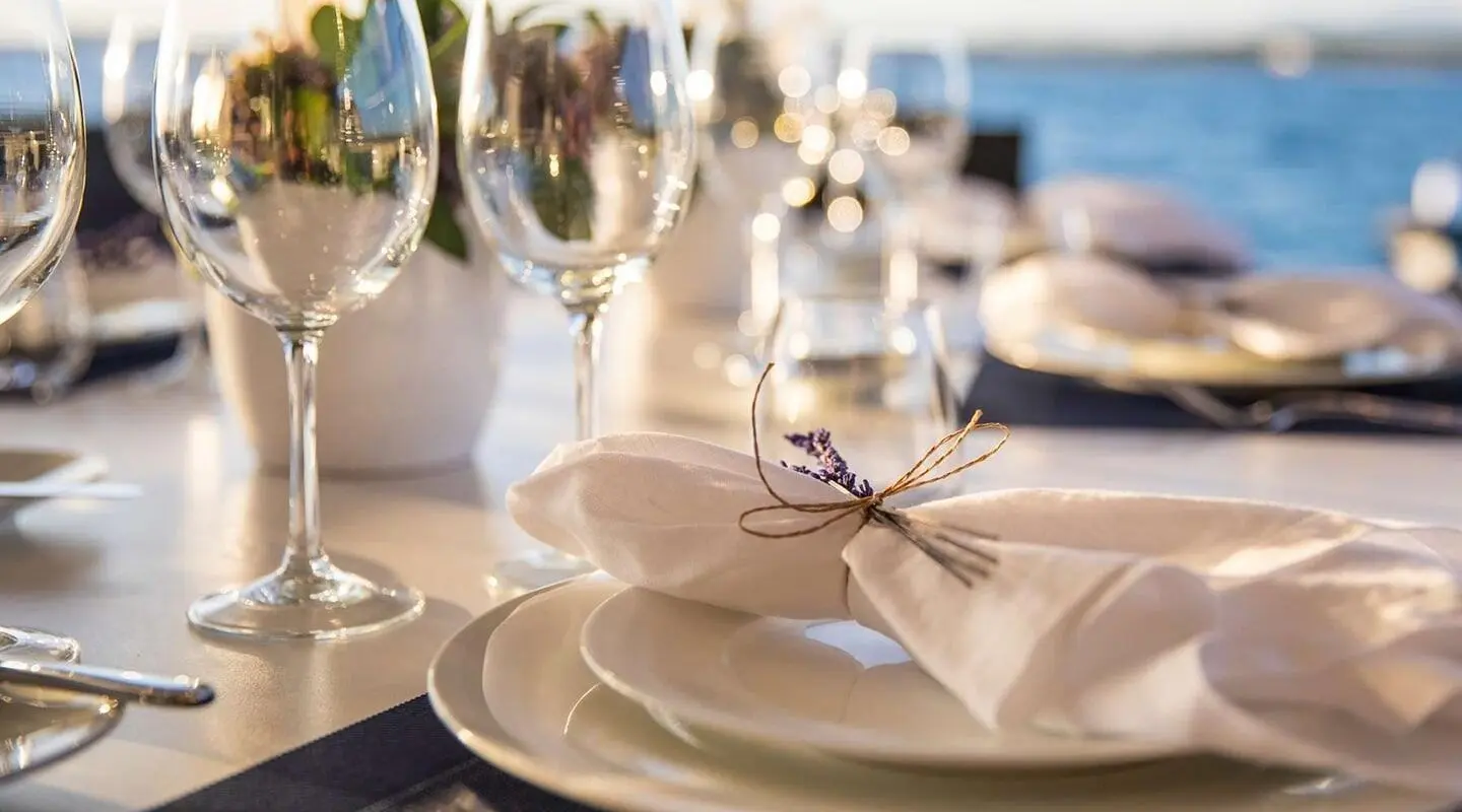 Cartouche yacht with masts at sunset, elegant table setup in foreground