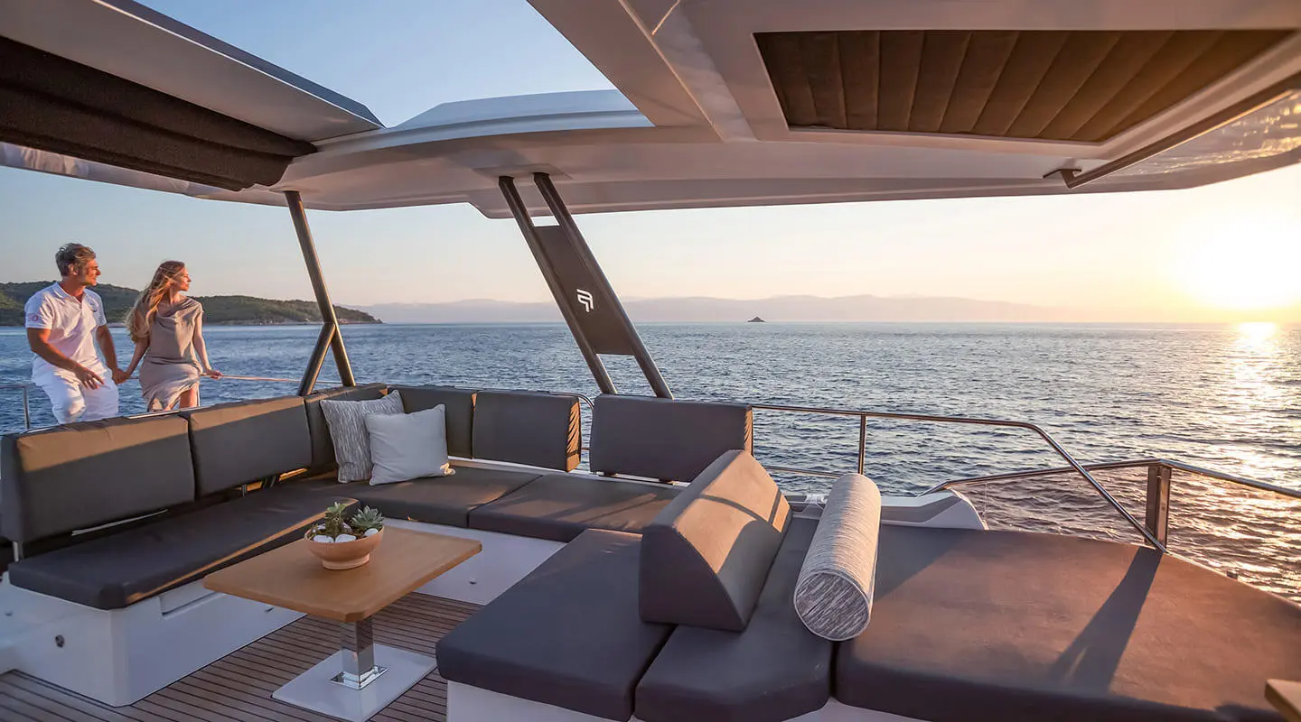 D2 motor yacht with aft deck seating and sun loungers over calm sea at sunset