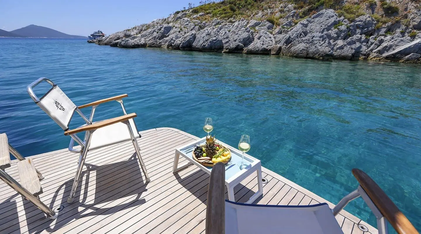 Gazella yacht deck at sunset with seating, railing, and blue water