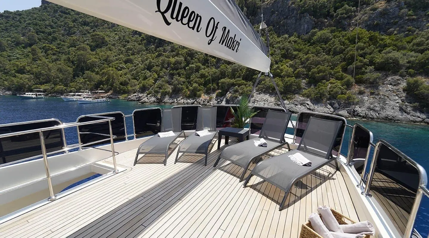Queen Of Makri yacht sun loungers on spacious aft deck with sea and rocky coastline