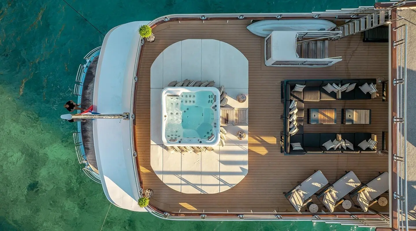 Top-down view of Freedom yacht deck with seating, sun loungers, and a hot tub