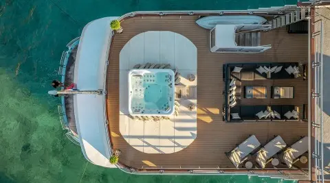 Top-down view of Freedom yacht deck with seating, sun loungers, and a hot tub