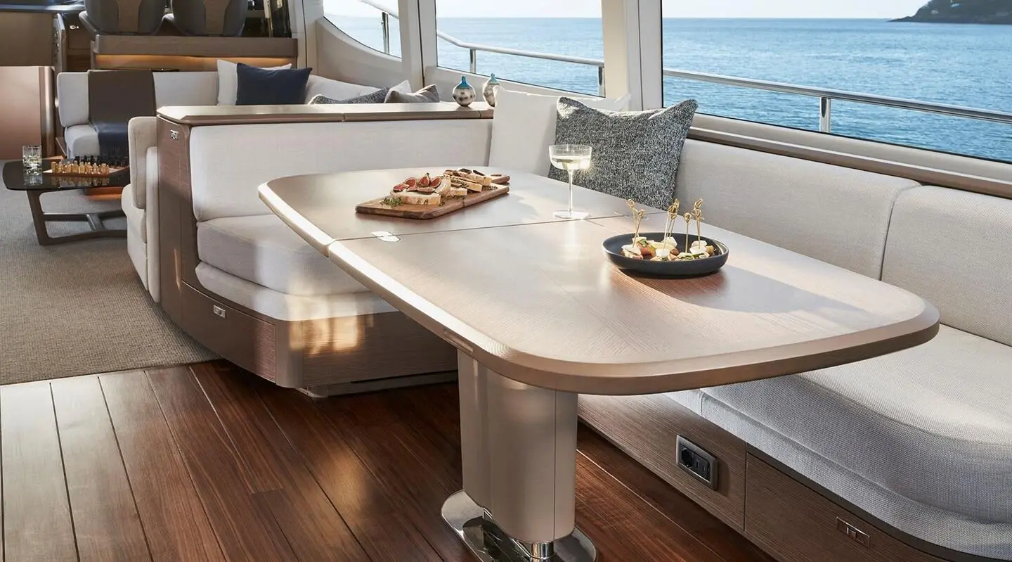 Yacht Elizabeth saloon with wooden table and white seating, framed by windows