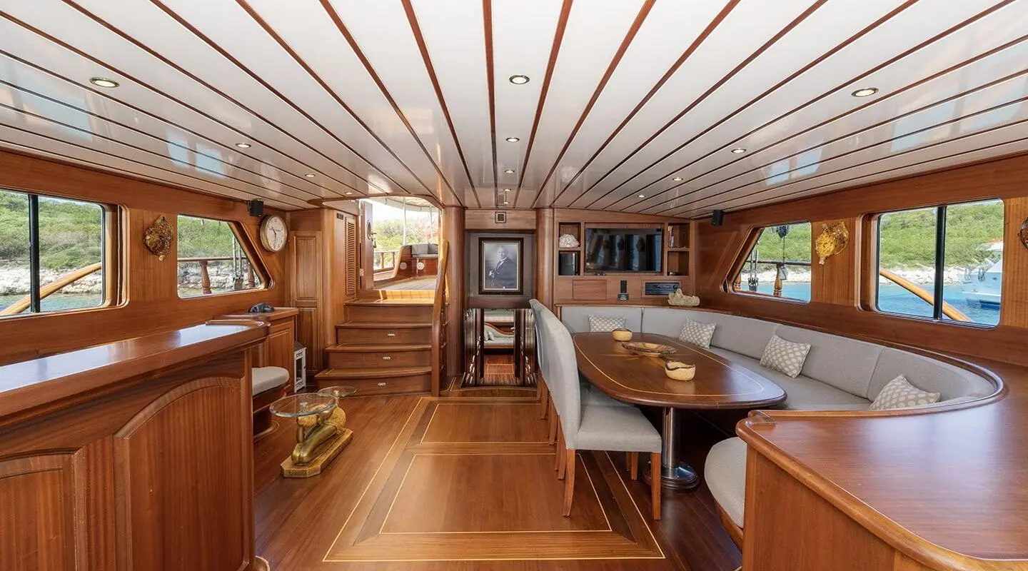 Interior of a luxury yacht with wooden deck, table, seating, and cabin details