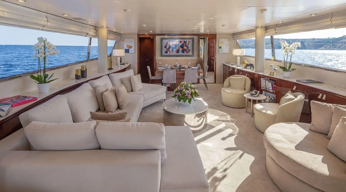 Spacious yacht saloon with cream seating, wooden panels, and large windows