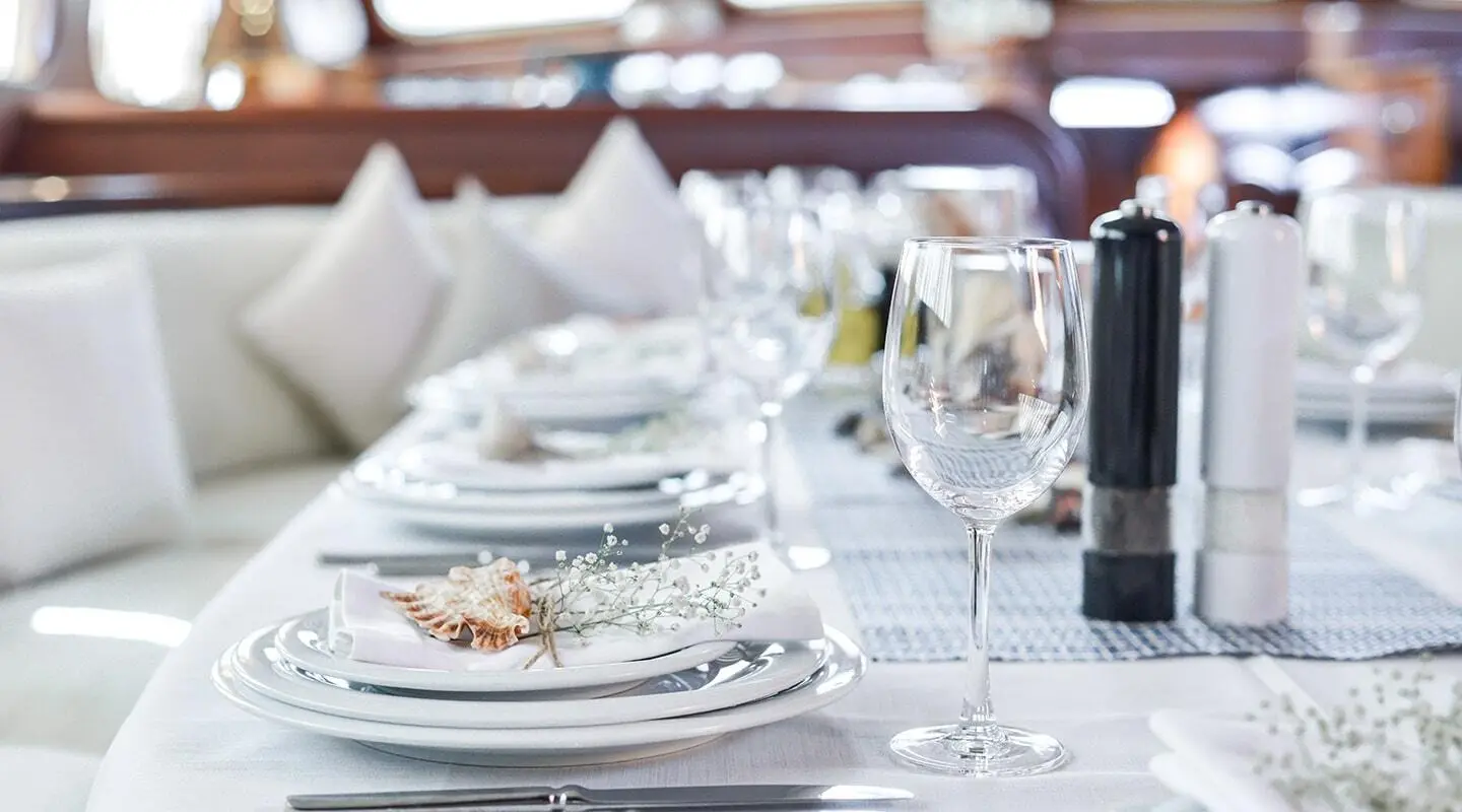 Lady Christa yacht at sunset with dining table set on deck and white napkins
