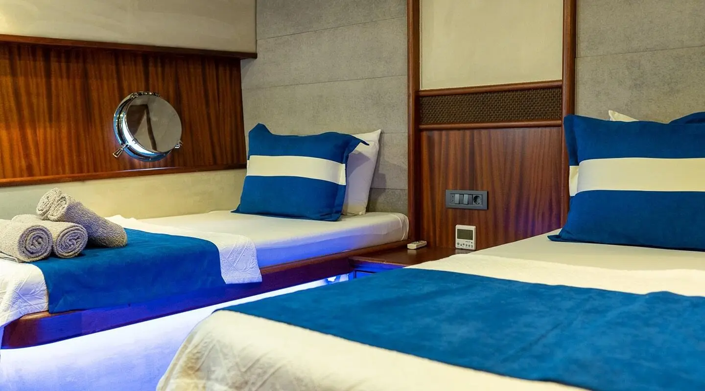 Nevra Queen yacht cabin with blue and white bedding and bedside lamp