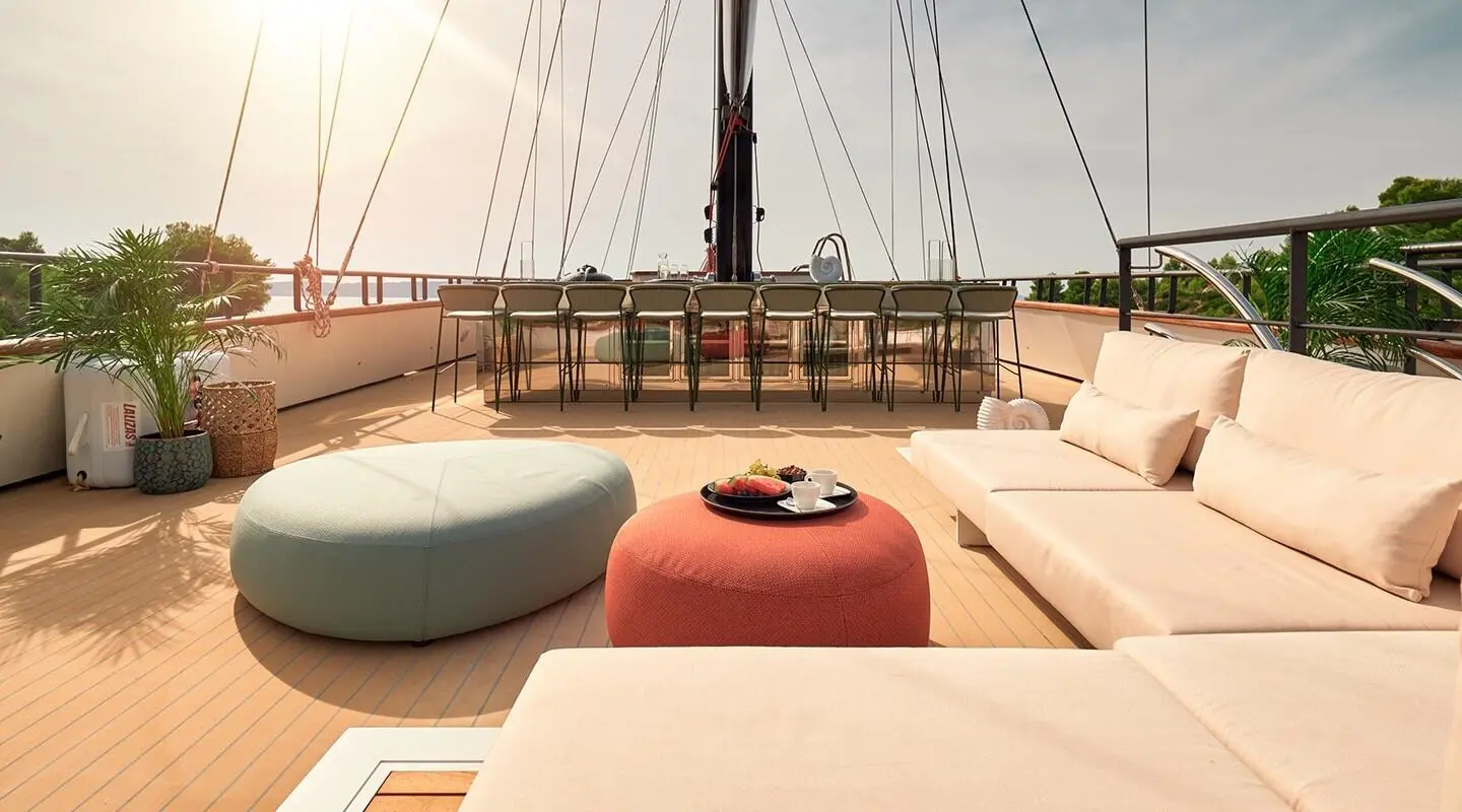On deck of Anetta yacht at sunset, lounge cushions, railing, and helm visible