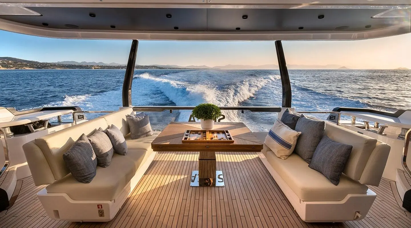 Spica yacht balcony seating with a table, ocean view at sunset