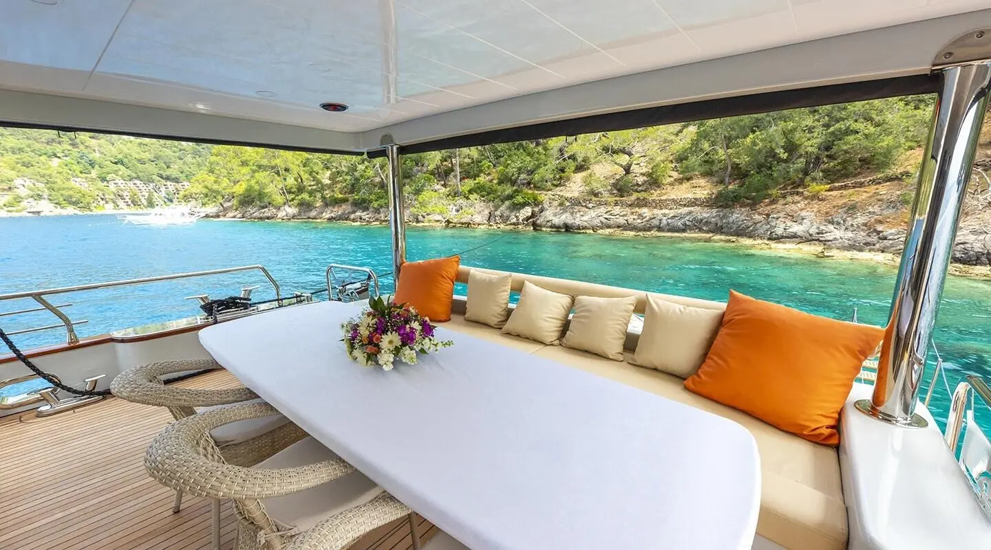 Sundeck seating area of Simay M yacht with orange cushions and a vase of flowers