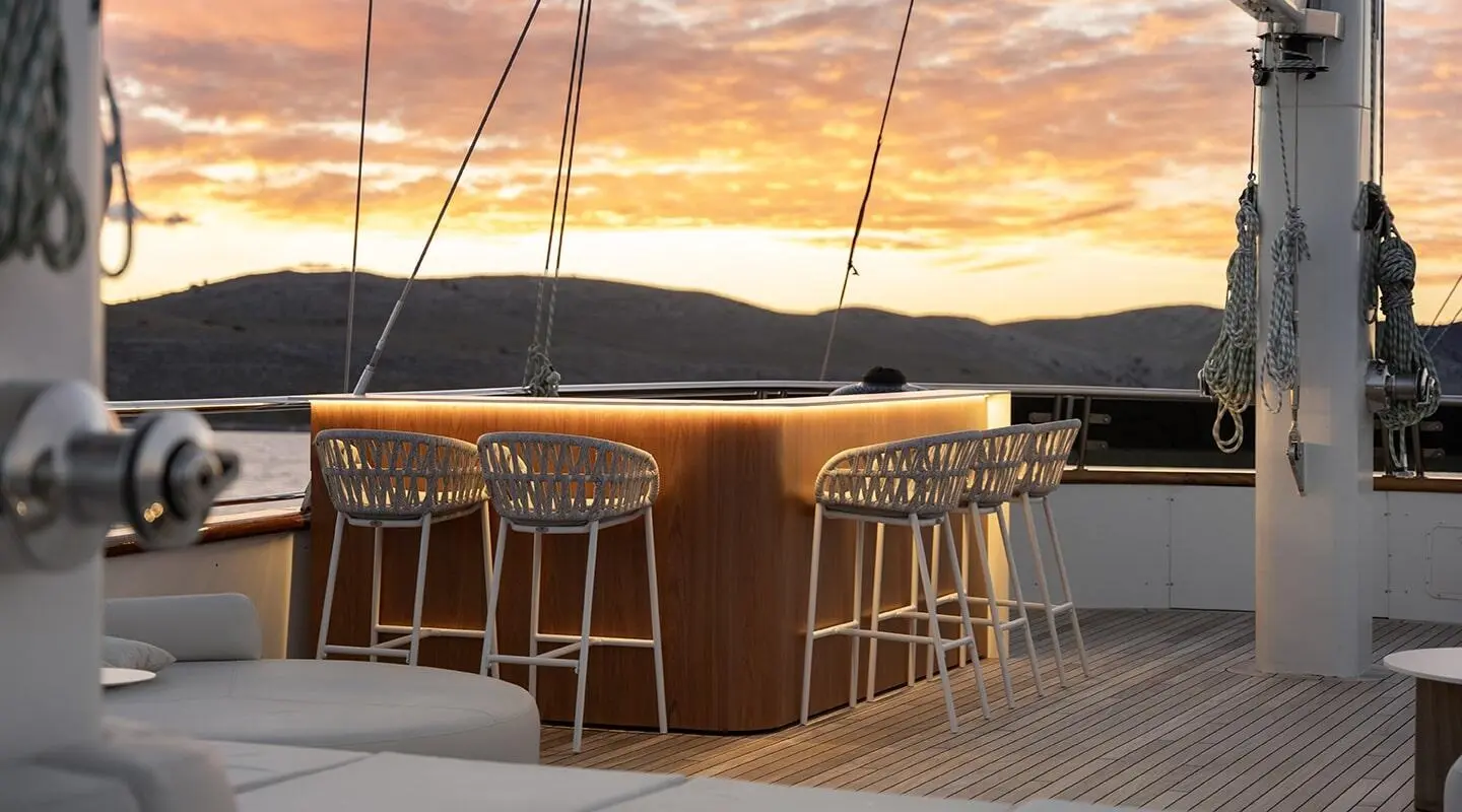 Maxita yacht exterior sunset bar with four white woven stools