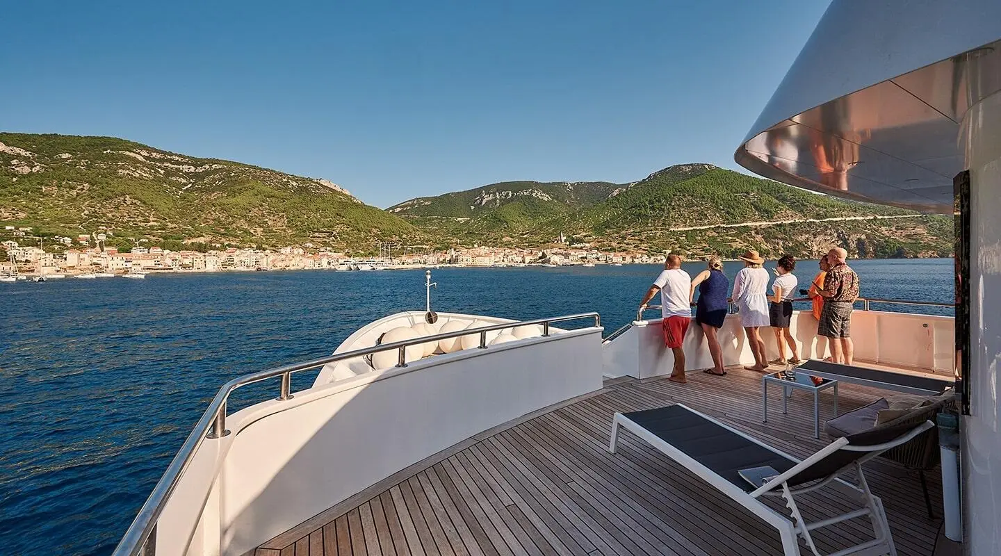 Lupus Mare yacht deck with people, calm blue sea and distant green hills