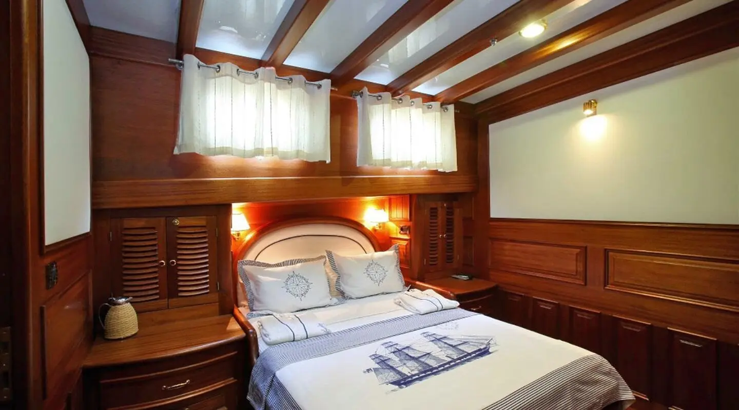 Kaya Guneri 4 yacht bedroom with wooden paneling and white bed linens