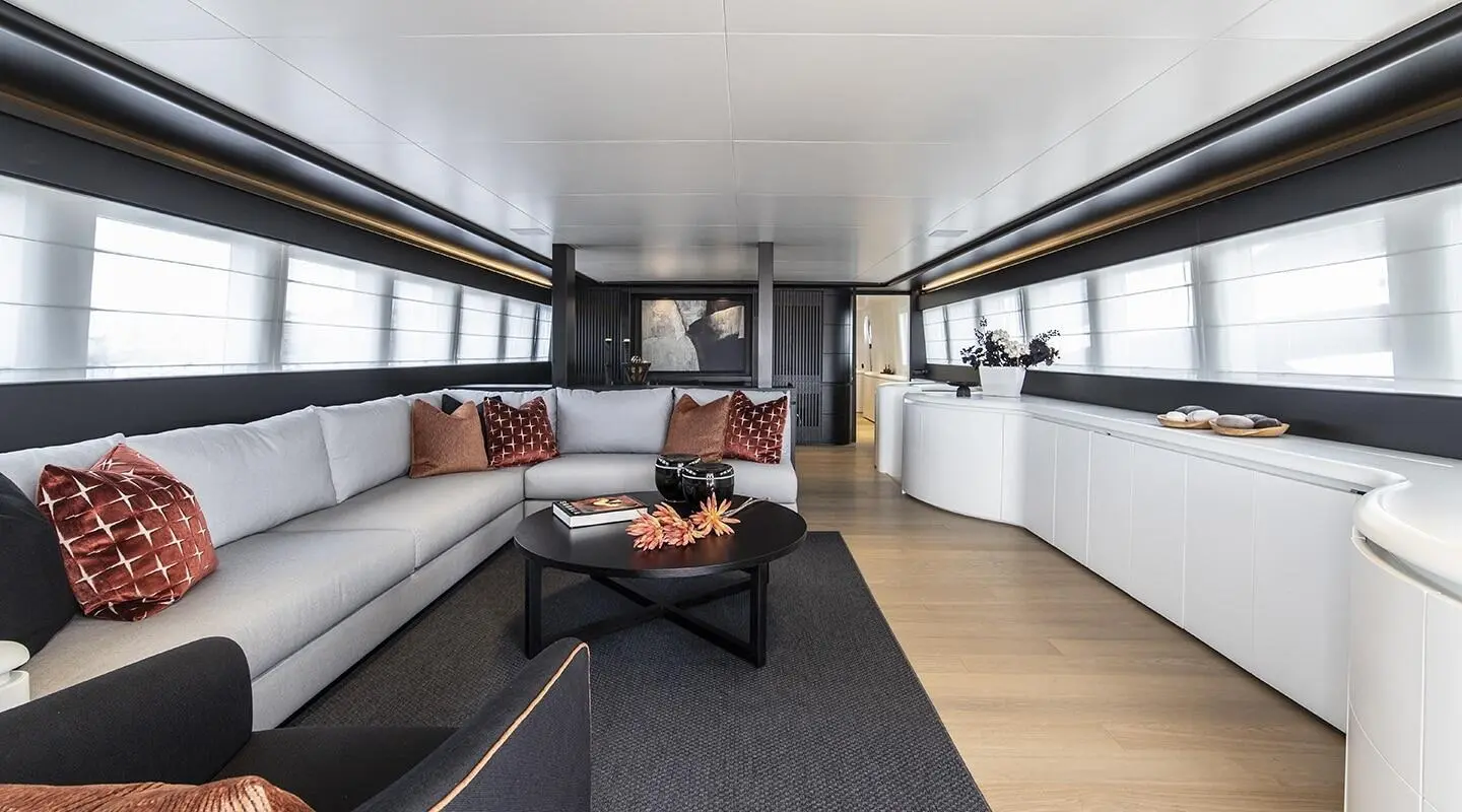 Elegant yacht salon with sofas, neutral tones, and a large windowed view