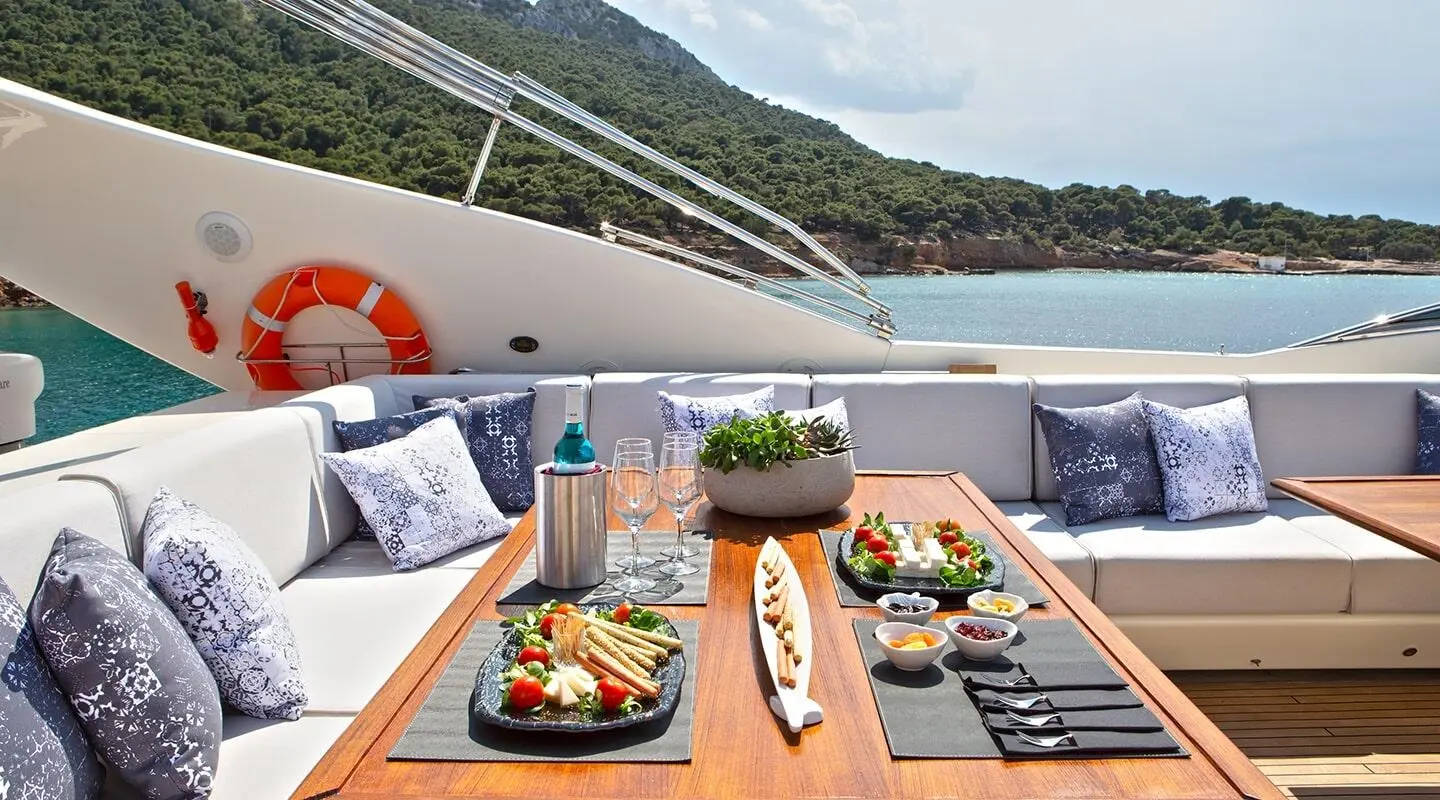 Onboard dining setup on Divine yacht with wooden table, plate of tapas, wine glass
