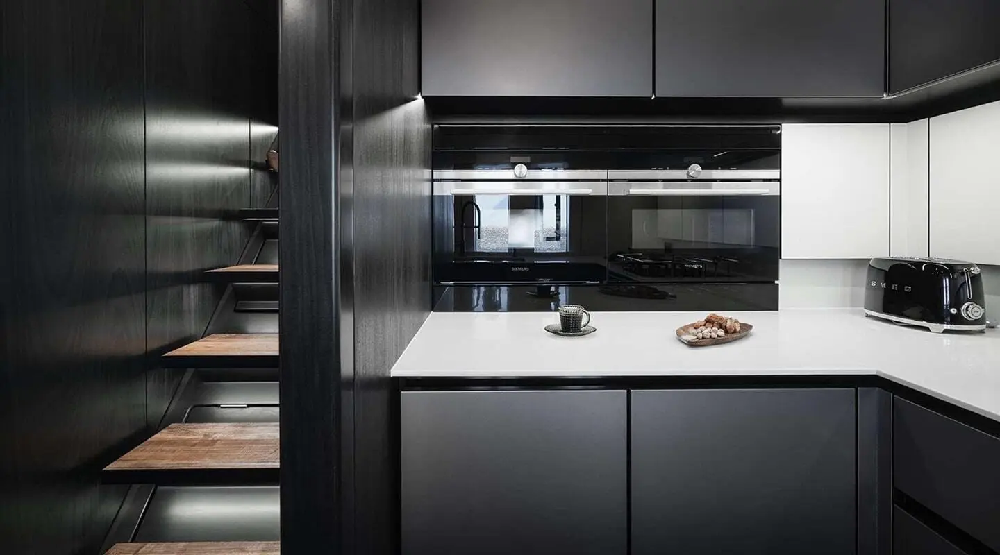 Sleek yacht galley with dark cabinets and bright countertop lighting