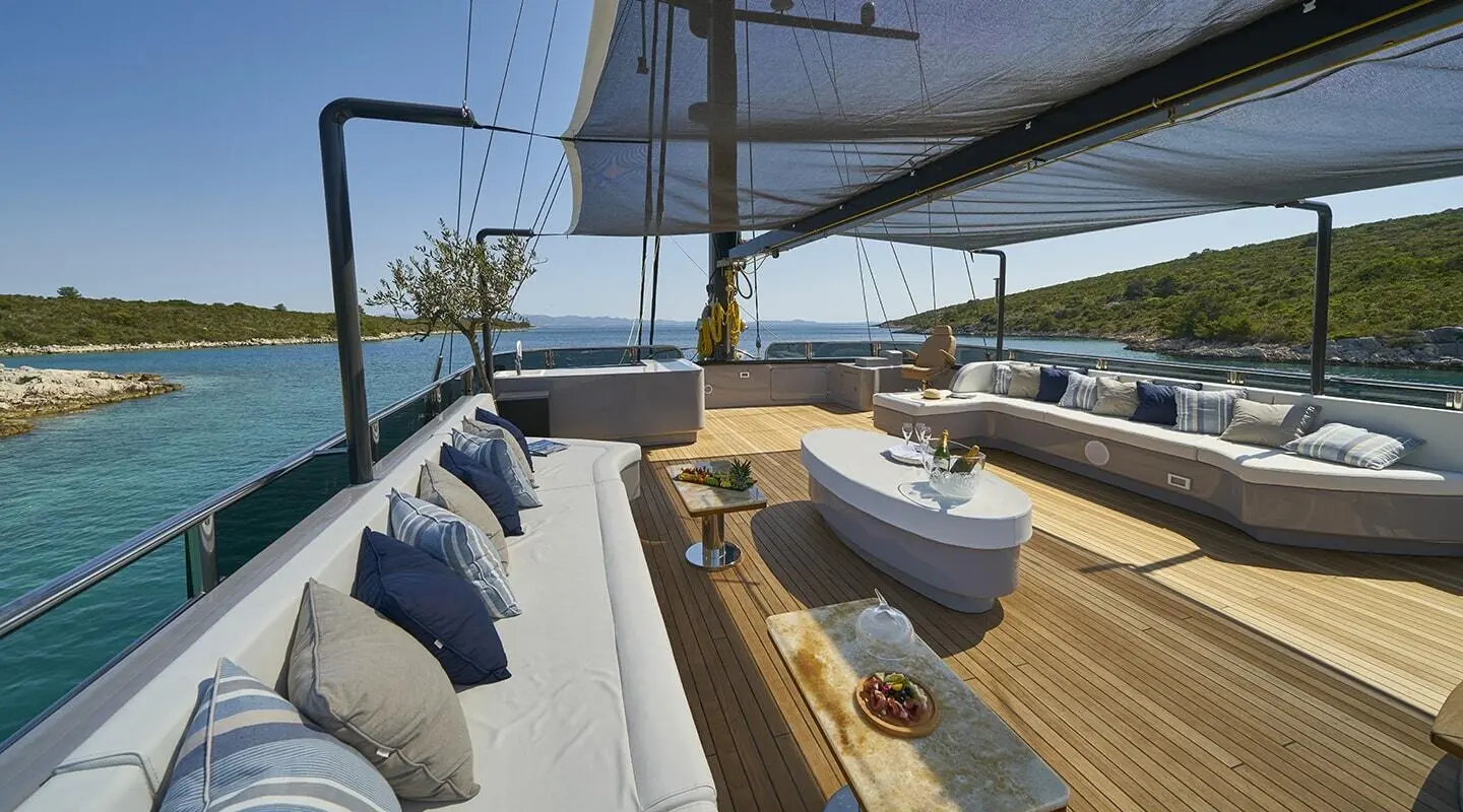 Rara Avis yacht deck with shaded seating, blue cushions, and ocean views