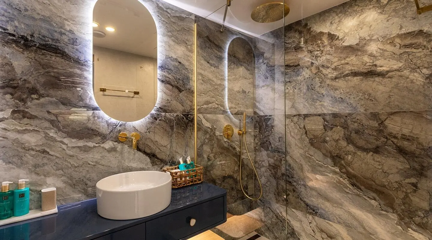Luxurious yacht Scorpios deck bathroom with stone walls, glass shower, and round sink