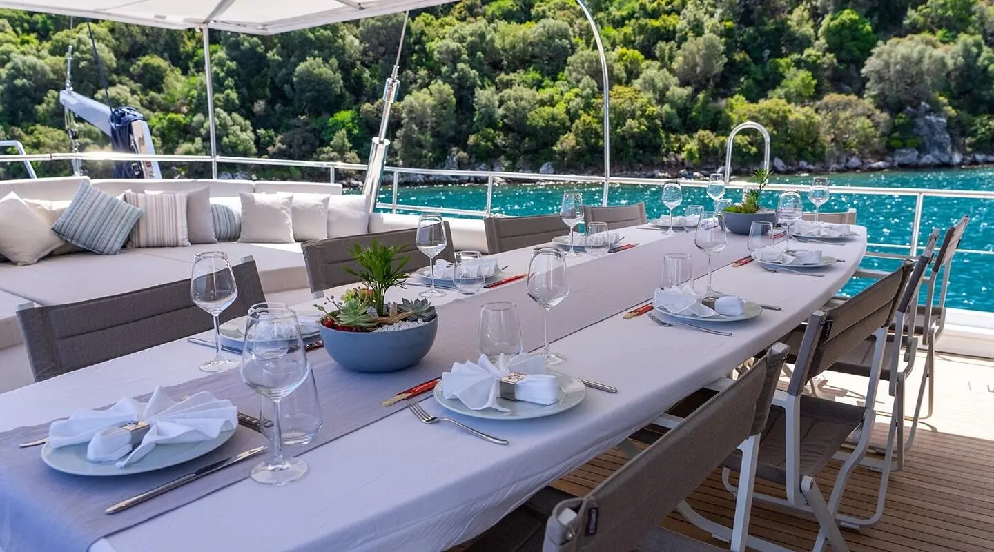 Good Life yacht dining setup on deck at sunset, white tablecloths and chairs