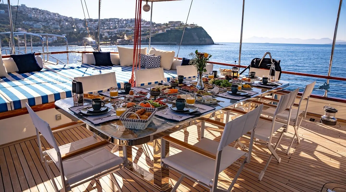 Gauzy rooftop dining setup on a yacht with tables and chairs, sea view backdrop