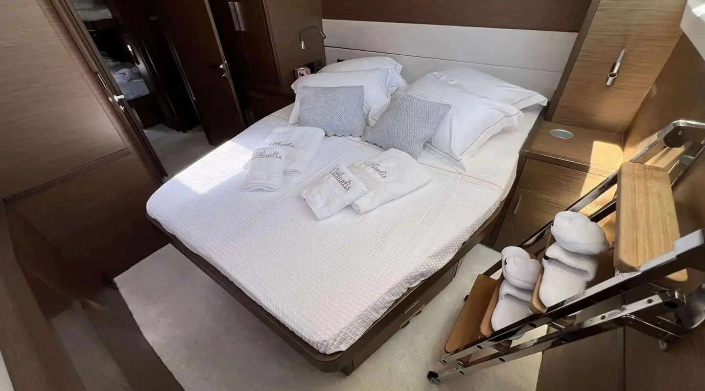 Atlantis yacht bedroom: neatly made bed with white linens and pillows