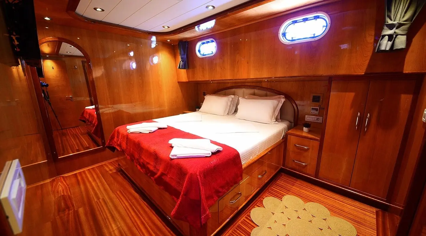 Cozy yacht cabin with wooden walls, bed, and warm lighting around Maya