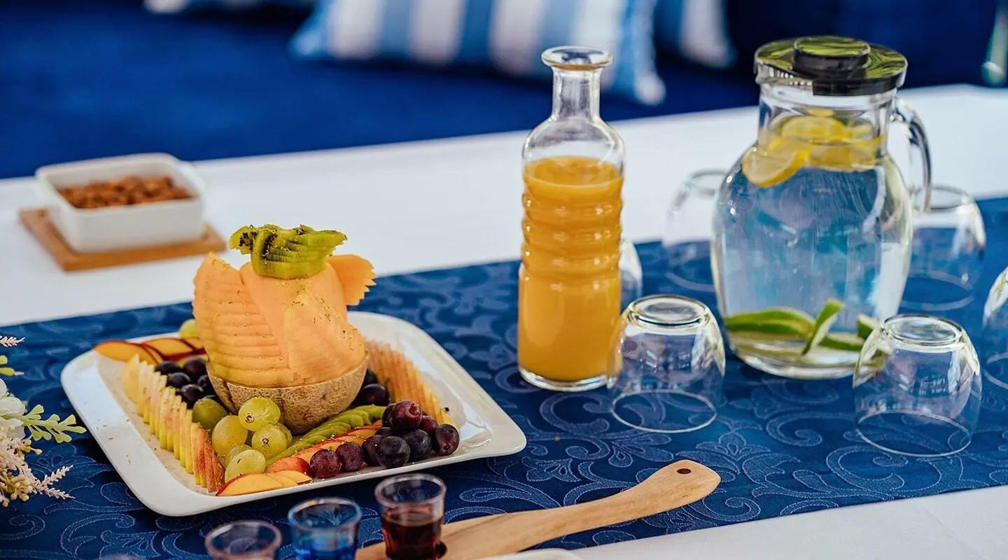 Maske yacht charter scene with a table of snacks, drinks, and sunset sea view