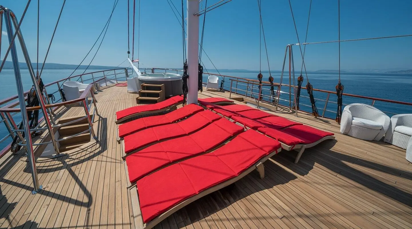Red sun loungers on the yacht deck with ropes and sea horizon