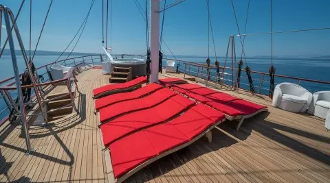 Red sun loungers on the yacht deck with ropes and sea horizon