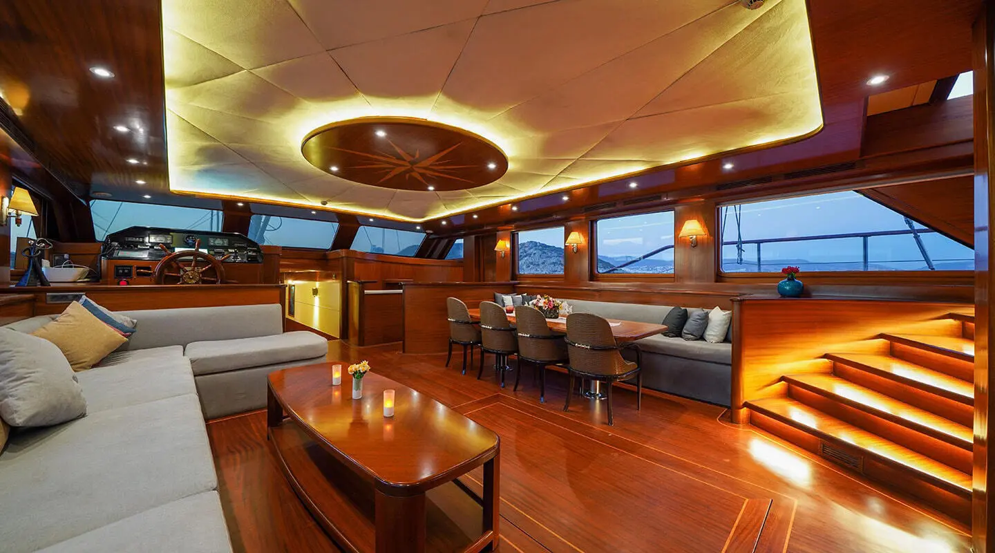 La Bella Vita yacht interior with wooden deck, seating, and warm lighting at dusk