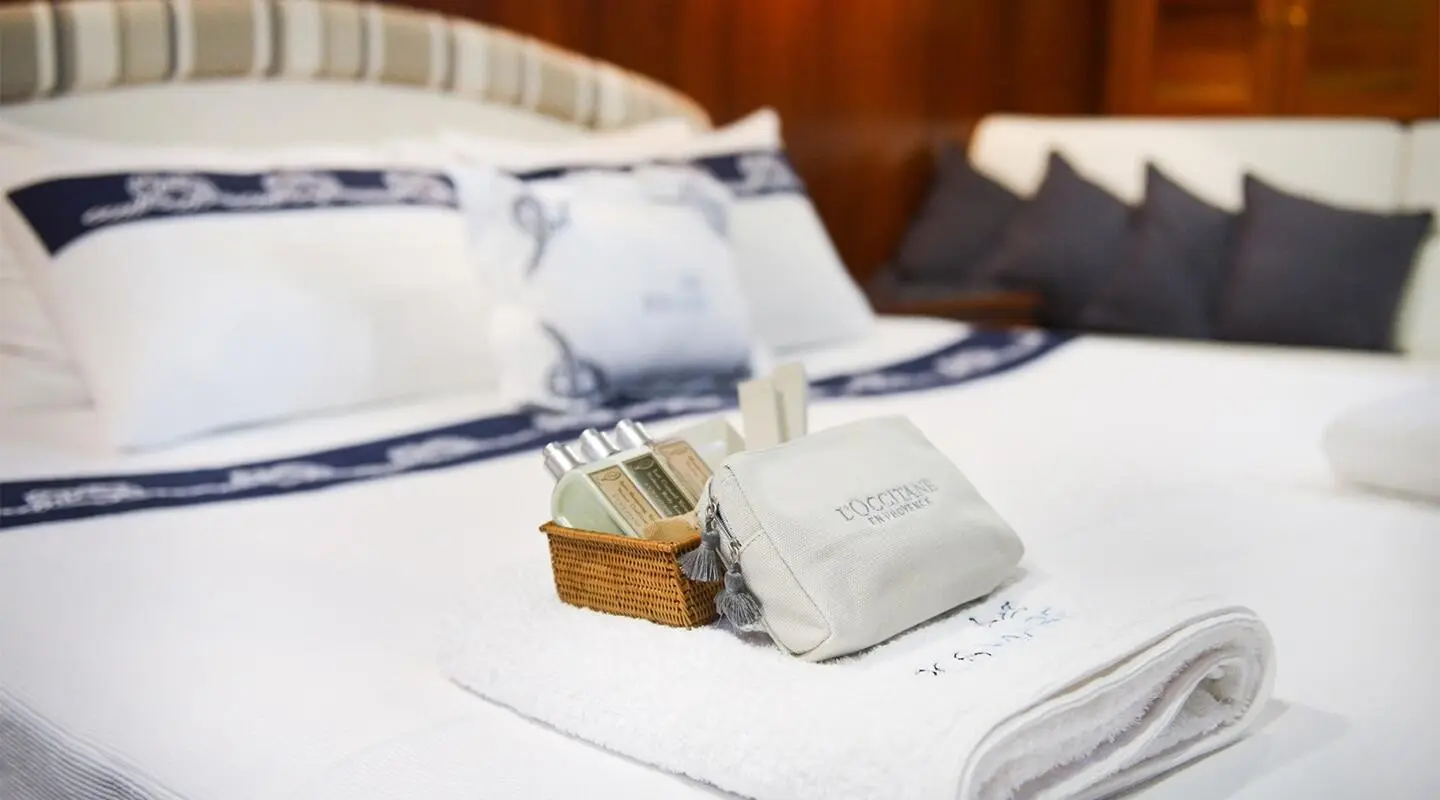 Yacht Ros Mare cabin with bed, white linens, and cushions visible in bright room