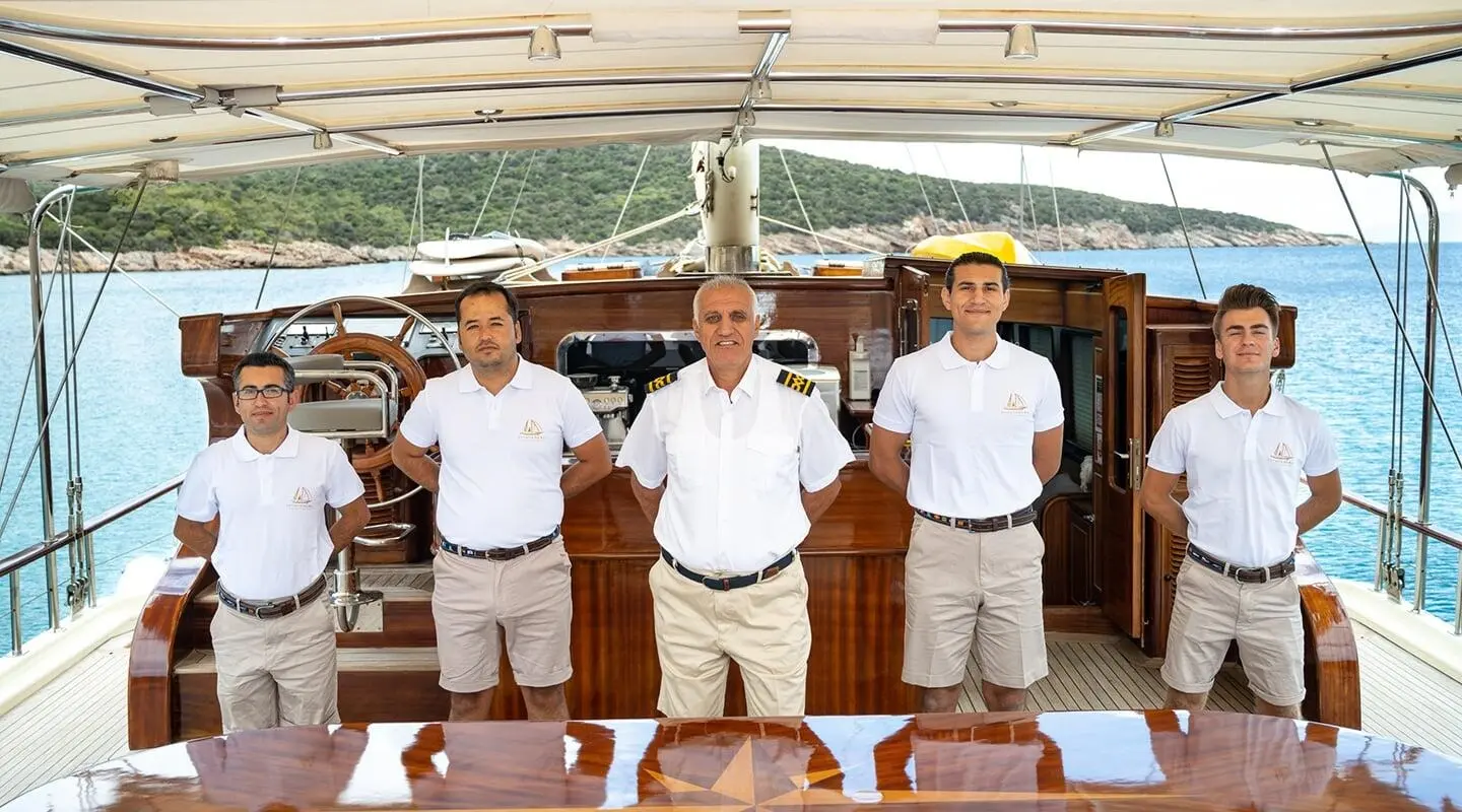 Estrella De Mar yacht crew standing on deck at sunset with railing and ocean view