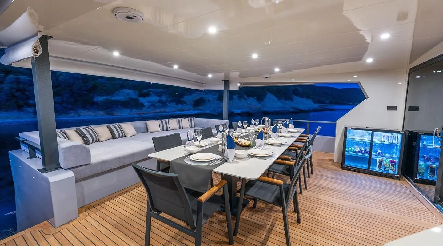 Calm Down yacht dining area at sunset with table set and seating on deck