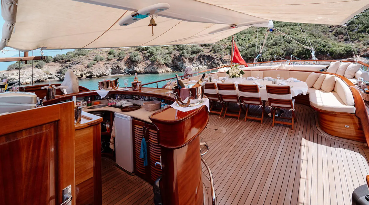 Lycian Queen yacht deck at sunset, wooden seating, white canopy, calm sea view