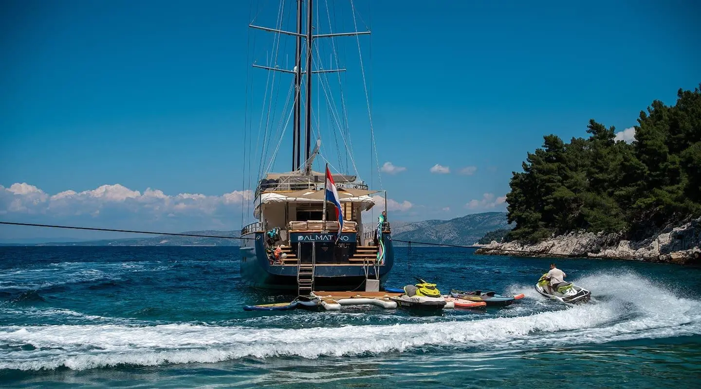 Dalmatino yacht anchored in blue sea with red hull and stern deck