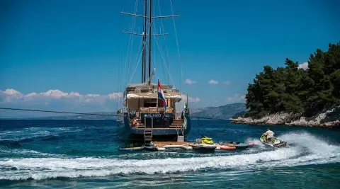 Dalmatino yacht anchored in blue sea with red hull and stern deck
