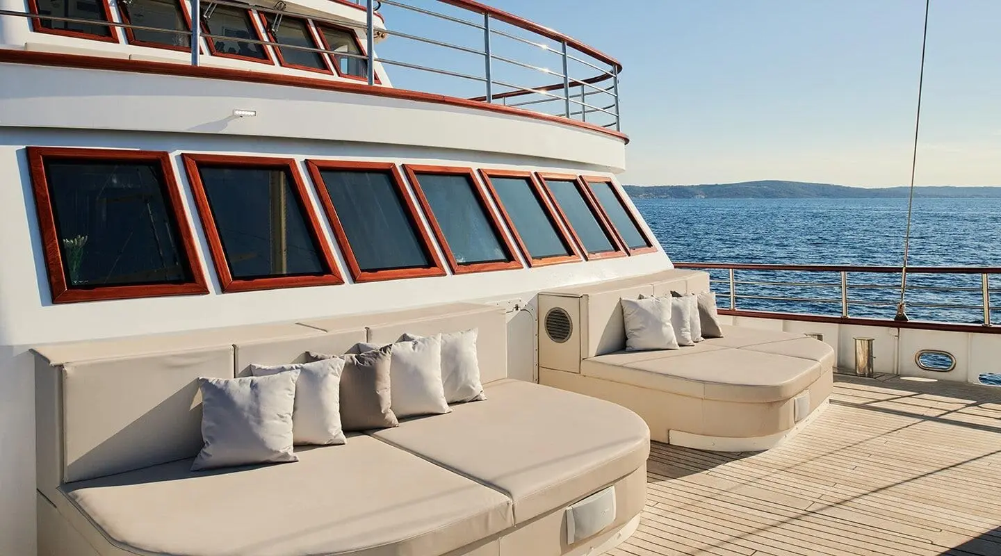 Corsario yacht deck with sun loungers and railing at sunset on calm sea