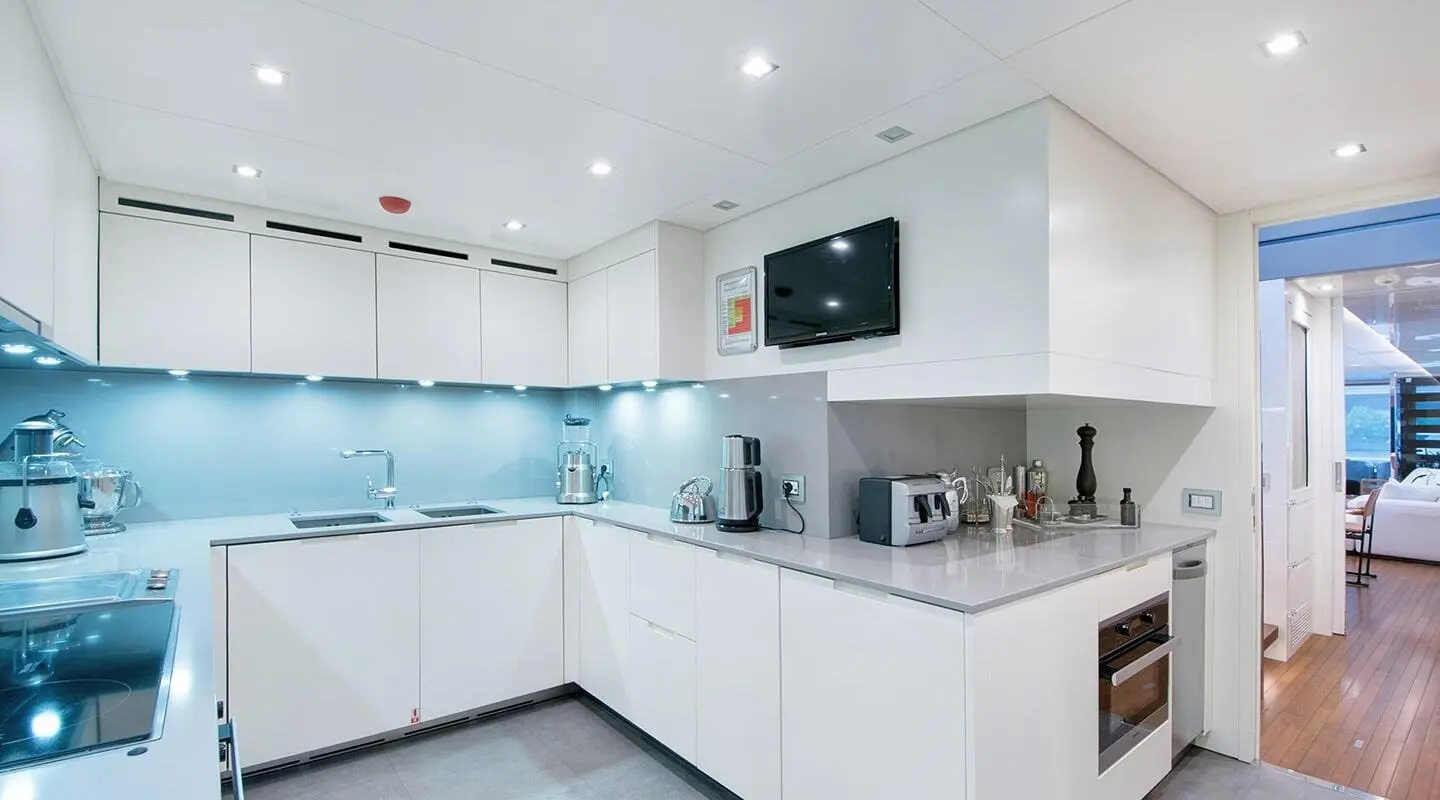 Morning Star yacht galley with white cabinets, blue-tiled backsplash, and kitchen appliances