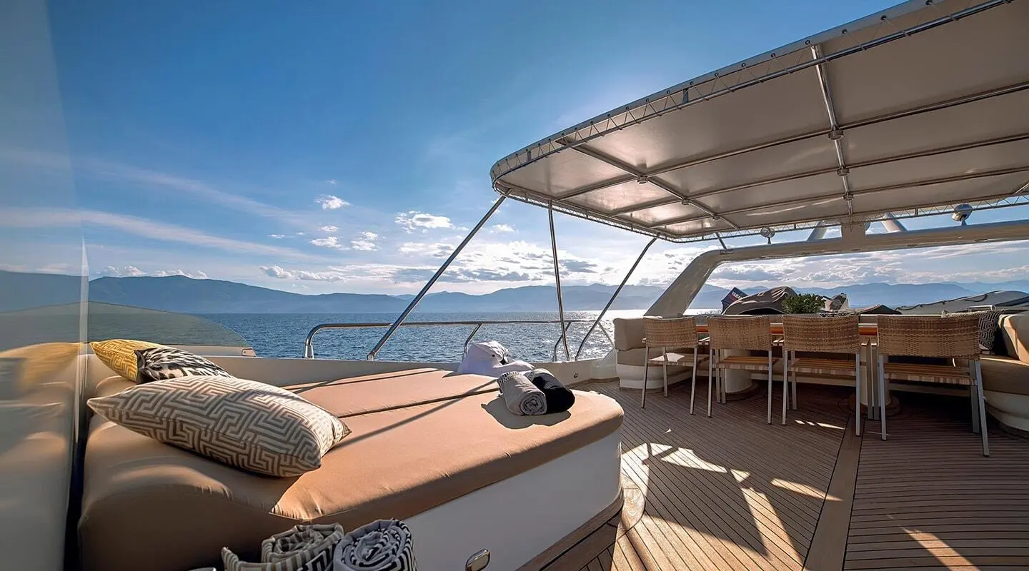 Aquila yacht deck at sunset with seating, railing, and harbor in distance
