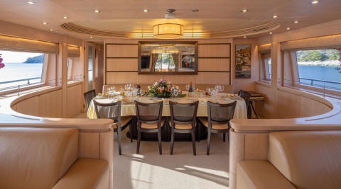 Interior of Glaros yacht with a long table set for dining and a large window view
