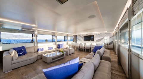 Sea Wolf interior: expansive saloon with light gray sofas, blue cushions, glass walls, and ocean view