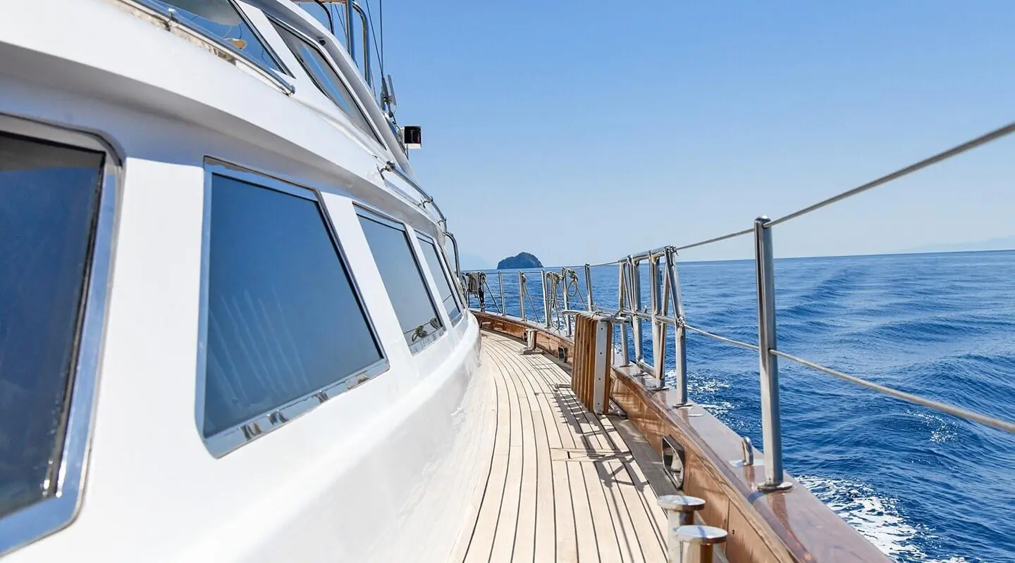 Side deck of Tamarita yacht with railing, blue ocean, clear sky