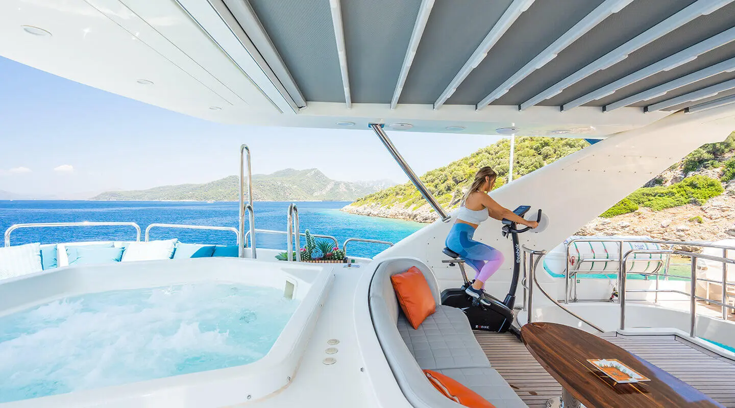 Amadea yacht deck with jacuzzi on ledge, blue sea beyond, sunlit seating