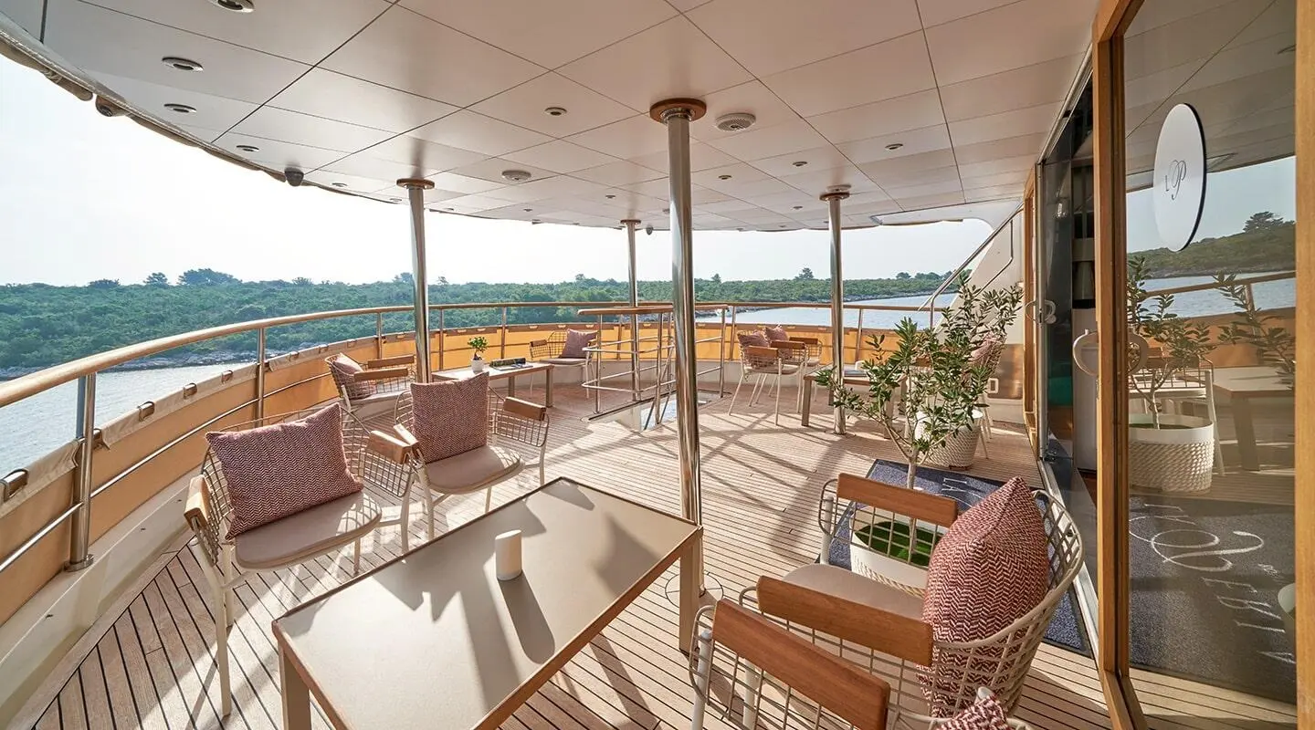 La Perla yacht aft deck with seating, sun loungers, and glass railing by calm sea
